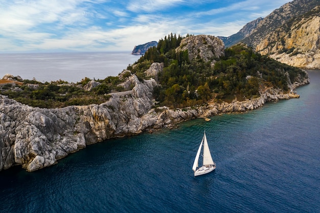 Yate navegando cerca de la costa rocosa en Turquía Vacaciones de lujo en el mar