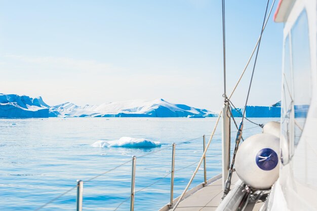 Yate navegando entre icebergs en el océano Atlántico en Groenlandia