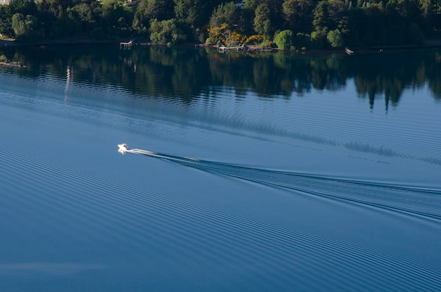 Yate navegando en un lago con aguas azules profundas dejando una estela en el agua