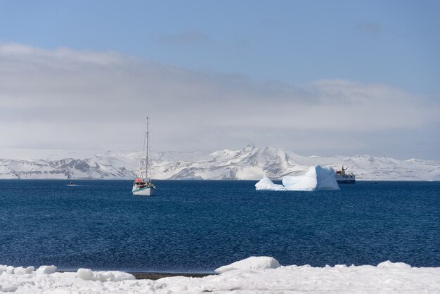 Yate de vela e iceberg en el mar antártico