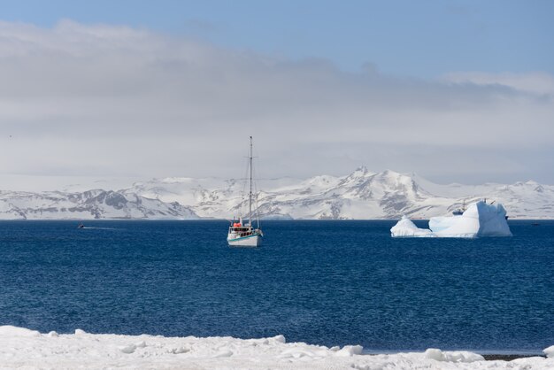 Yate de vela e iceberg en el mar antártico