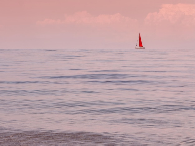 Yate con una vela roja escarlata al atardecer en la isla de Cefalonia en el Mar Jónico en Grecia