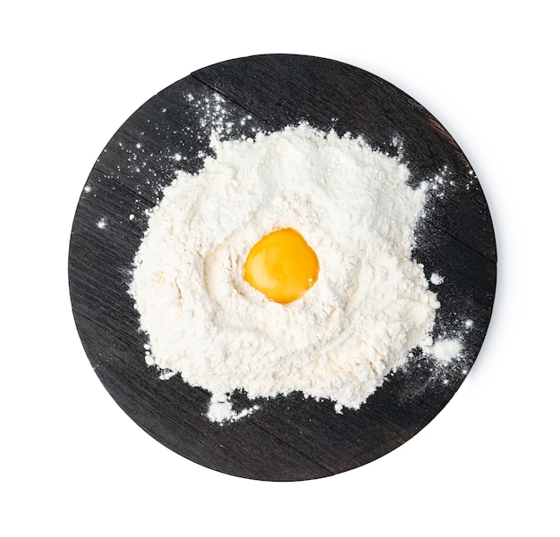 Yema de huevo cruda en montón de harina sobre fondo blanco.
