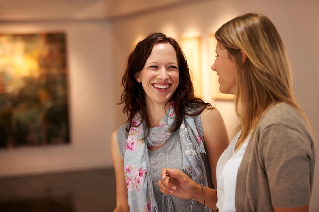 Yo tampoco lo entiendo Dos mujeres jóvenes se ríen juntas mientras asisten a una exhibición de arte