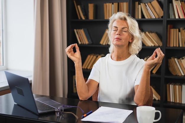 Yoga, Achtsamkeit, Meditation, kein Stress, ruhig bleiben, mittelalterliche Frau übt Yoga im Büro, Frau