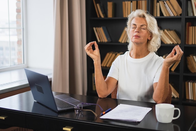 Yoga, Achtsamkeit, Meditation, kein Stress, ruhig bleiben, mittelalterliche Frau übt Yoga im Büro, Frau
