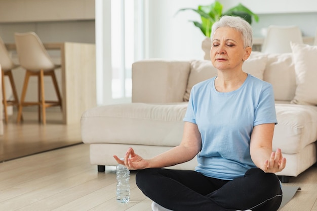 Yoga, Achtsamkeitsmeditation, ältere Erwachsene, reife Frau, die zu Hause Yoga übt, mittlere Alters-Alterin