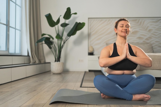 Yoga Achtsamkeitsmeditation Frau übt Yoga im Wohnzimmer zu Hause plus Größe Frau sitzt in