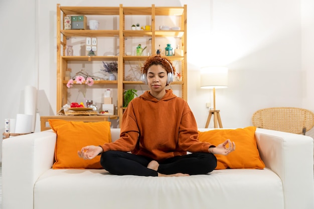 Yoga-Achtsamkeitsmeditation Junges gesundes afrikanisches Mädchen, das Yoga zu Hause praktiziert Frau, die in Lotus sitzt