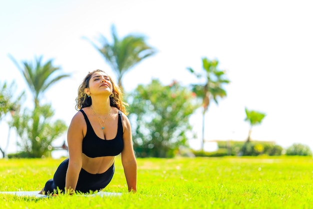 Yoga al aire libre mujer haciendo yoga en el parque verde de verano en un día soleado