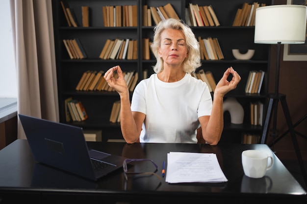 Yoga atención plena meditación sin estrés mantener la calma mujer de mediana edad practicando yoga en la oficina mujer