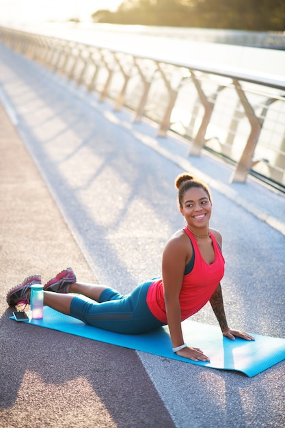 Yoga auf der Brücke. Strahlende schöne Frau, die Sportkleidung trägt, die Yoga auf der Brücke tut