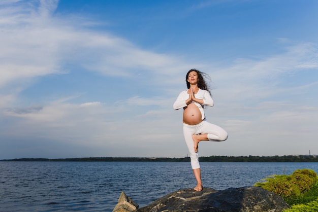 Yoga-Baum-Pose durch schwangere Frau.