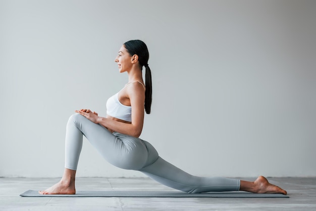 Yoga-Übungen machen Frau mit sportlich schlankem Körpertyp in Unterwäsche, die im Studio ist