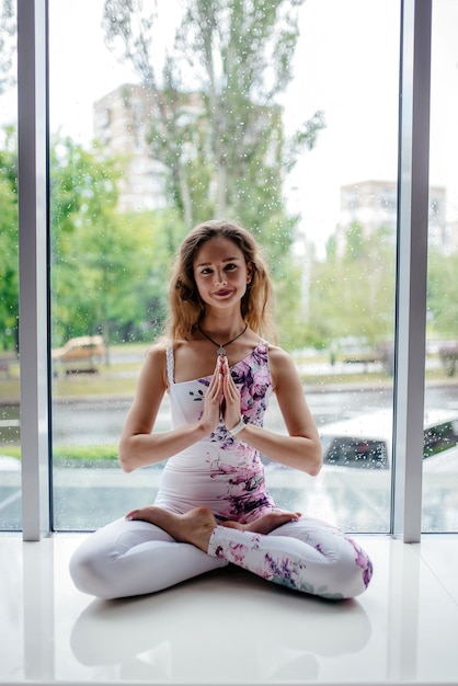 Yoga em casa Mantenha a calma Jovem atraente sentada na posição de lótus no chão com os olhos fechados