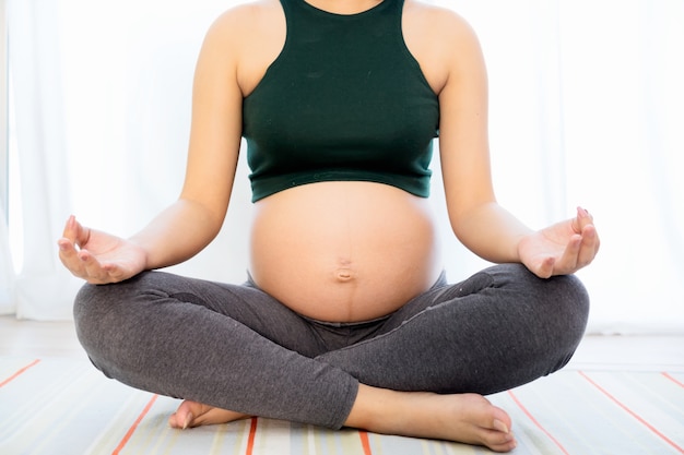 Yoga de embarazo Joven mujer embarazada haciendo yoga en casa.