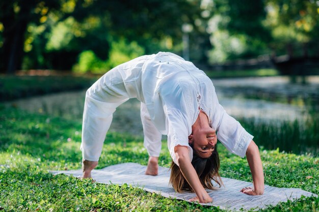 Yoga-Frau, die Brückenhaltung tut, natürlicher grüner Hintergrund