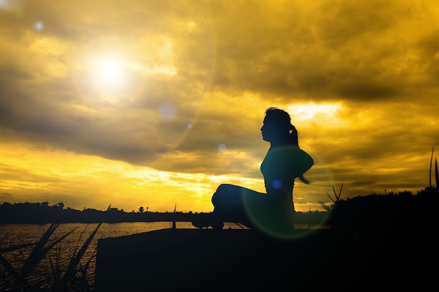 Yoga im Schattenbild mit drastischem Sonnenunterganghimmelhintergrund