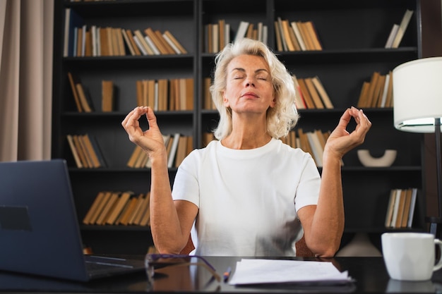 Foto yoga meditação atenciosa sem estresse manter a calma mulher de meia-idade praticando ioga no escritório mulher