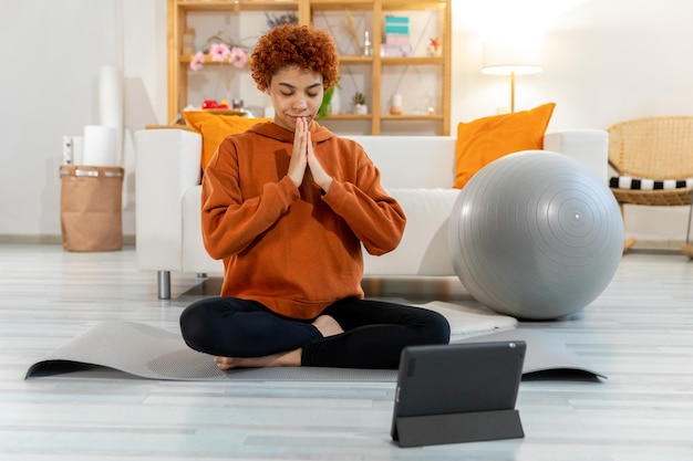 Yoga meditación de atención plena joven joven africana sana practicando yoga en casa mujer sentada en