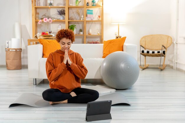 Yoga mindfulness meditação jovem garota africana saudável praticando yoga em casa mulher sentada em lotu