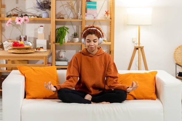 Yoga mindfulness meditação jovem garota africana saudável praticando yoga em casa mulher sentada em lotu