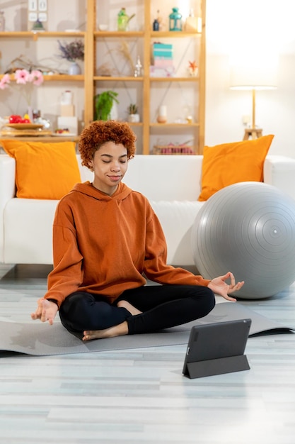 Yoga mindfulness meditación joven niña africana sana practicando yoga en casa mujer sentada en lotu