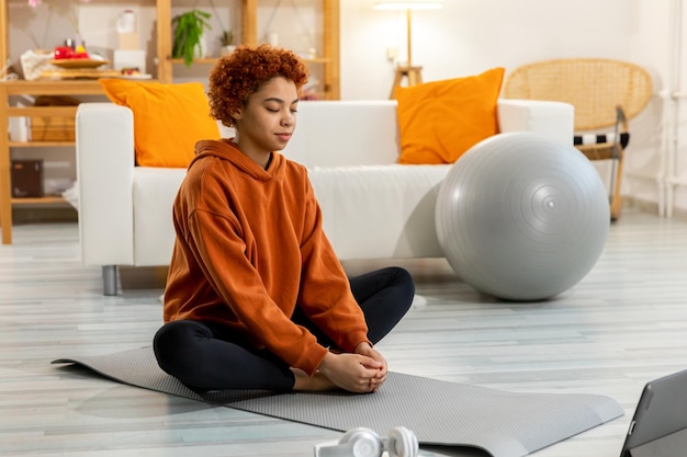 Yoga mindfulness meditación joven niña africana sana practicando yoga en casa mujer sentada en lotu