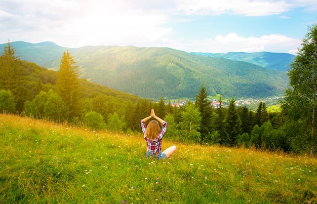 Yoga en la montaña. Hermosa chica está meditando en asana. increíble naturaleza de verano alrededor. Concepto de armonía y pasión por los viajes. Hipster viajando. Mujer elegante disfrutando de la vida.