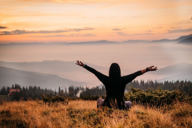 Yoga mujer sentada en la cima de una montaña al amanecer.