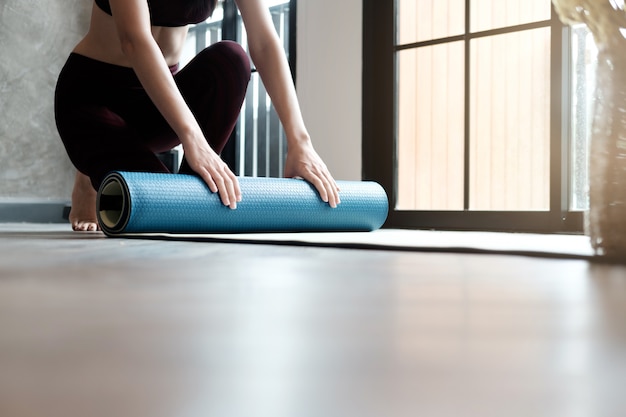 Yoga mulher rolando seu tapete lilás depois de uma aula de ioga