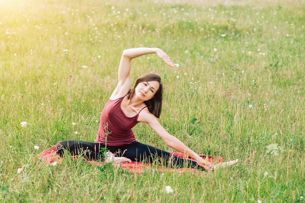 Yoga para niñas. Bella mujer en el campo haciendo yoga con una sonrisa