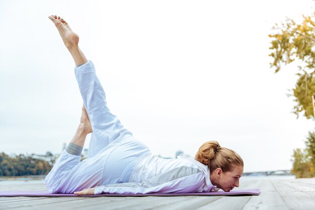 Yoga praktizieren. Frau, die leicht Yoga-Sträußchen praktiziert, während sie Yoga im Freien macht