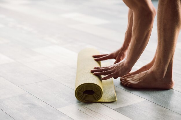 Foto yoga-training, sport- und fitness-wellness-lifestyle und regelmäßiges training im fitnessstudio, nicht erkennbarer mann, der eine matte ausrollt, um mit dem training zu beginnen