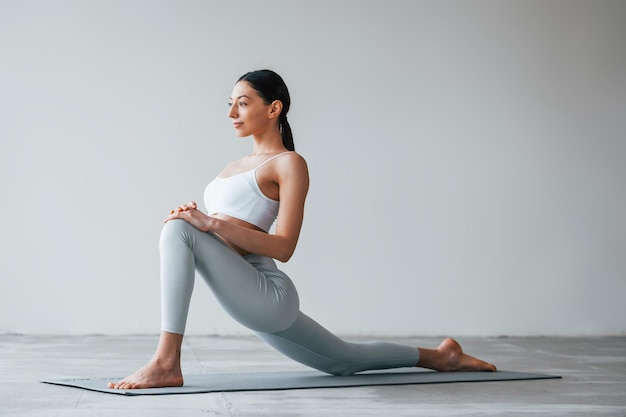 Yoga-Übungen machen Frau mit sportlich schlankem Körpertyp in Unterwäsche, die im Studio ist