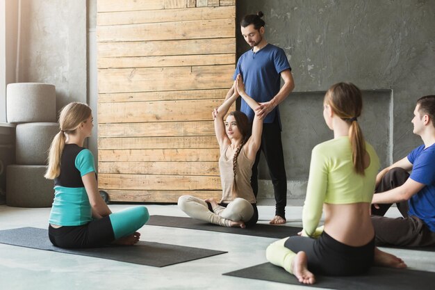 Yogalehrer und Anfänger in der Klasse, die Asana-Übungen machen. Lotus-Pose. Gesunder Lebensstil im Fitnessclub. Dehnen mit Trainer