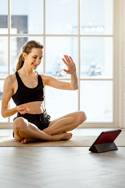 Foto yogalehrerin, die zu hause einen virtuellen yogakurs auf einer videokonferenz durchführt