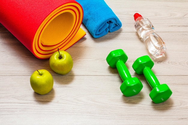 Yogamatte und verschiedene Fitnessgeräte auf dem Boden im Zimmer