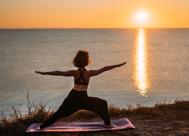 Yogi Frau praktiziert Yoga bei Sonnenaufgang am Meer