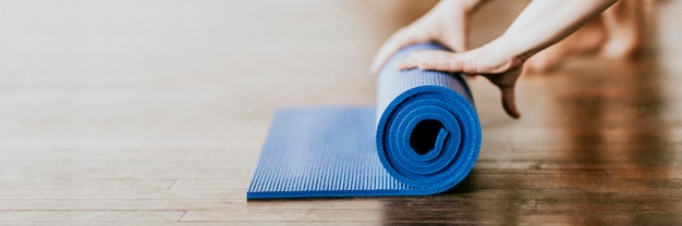 Yogi rollt ihre blaue Yogamatte