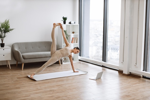 Yogini mejorando la fuerza del cuerpo mientras sostiene la postura de tabla lateral con la pierna levantada