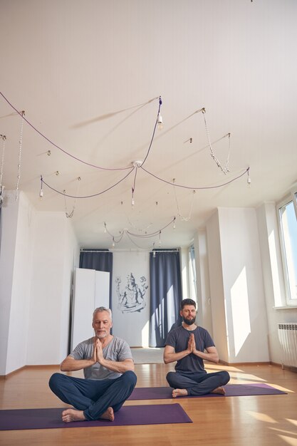 Yoguis profesionales relajados tranquilos sentados con las manos juntas en una asana de yoga durante el entrenamiento