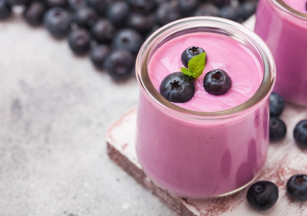 Yogur de arándanos cremoso casero fresco con arándanos frescos sobre tabla de madera vintage en mesa de piedra