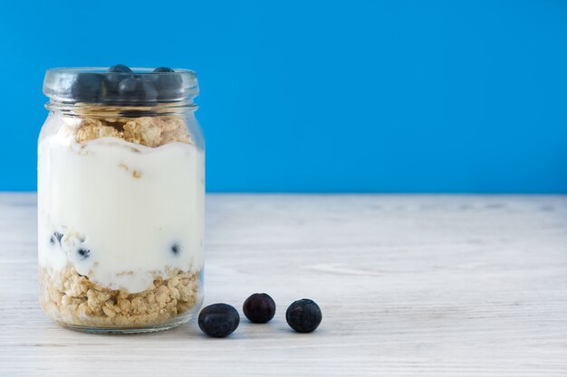 Yogur con arándanos en el espacio de copia de mesa de madera blanca