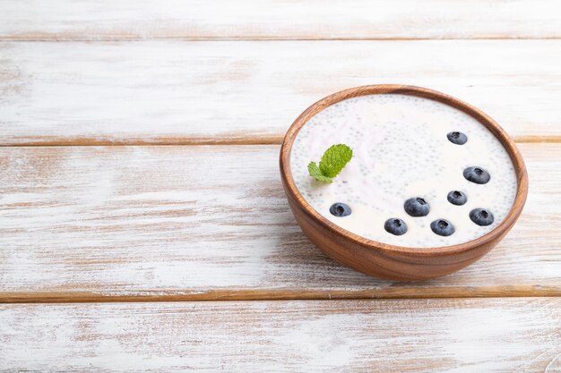 Yogur con arándanos en un tazón de madera sobre fondo blanco de madera Espacio de copia de vista lateral