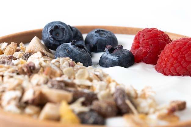 Yogur con bayas y muesli para desayunar en un recipiente aislado de fondo blanco