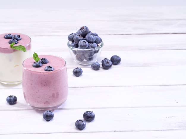 Yogur blanco y yogur de arándanos en mesa de madera