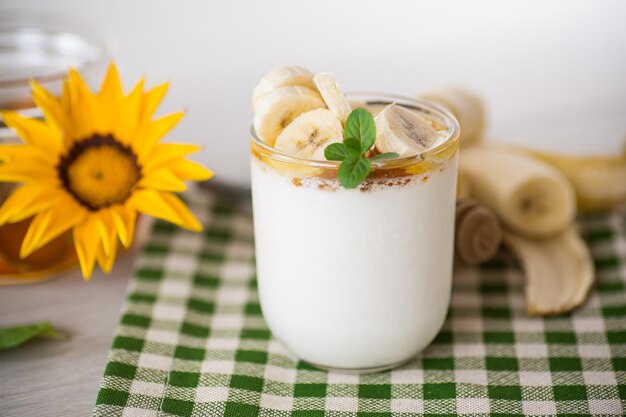 Yogur casero dulce con plátanos y miel en un vaso