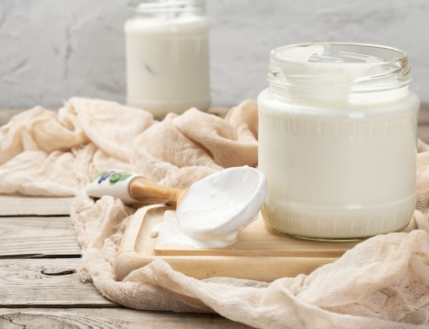 Yogur casero en un frasco de vidrio transparente sobre una mesa de madera, un producto lácteo fermentado saludable