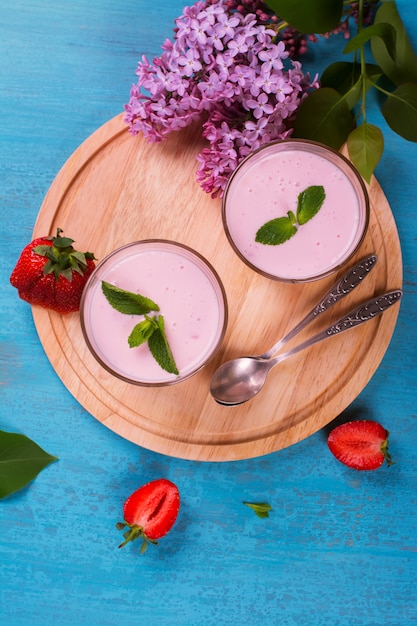 Yogur casero con fresas frescas y menta sobre fondo de madera azul